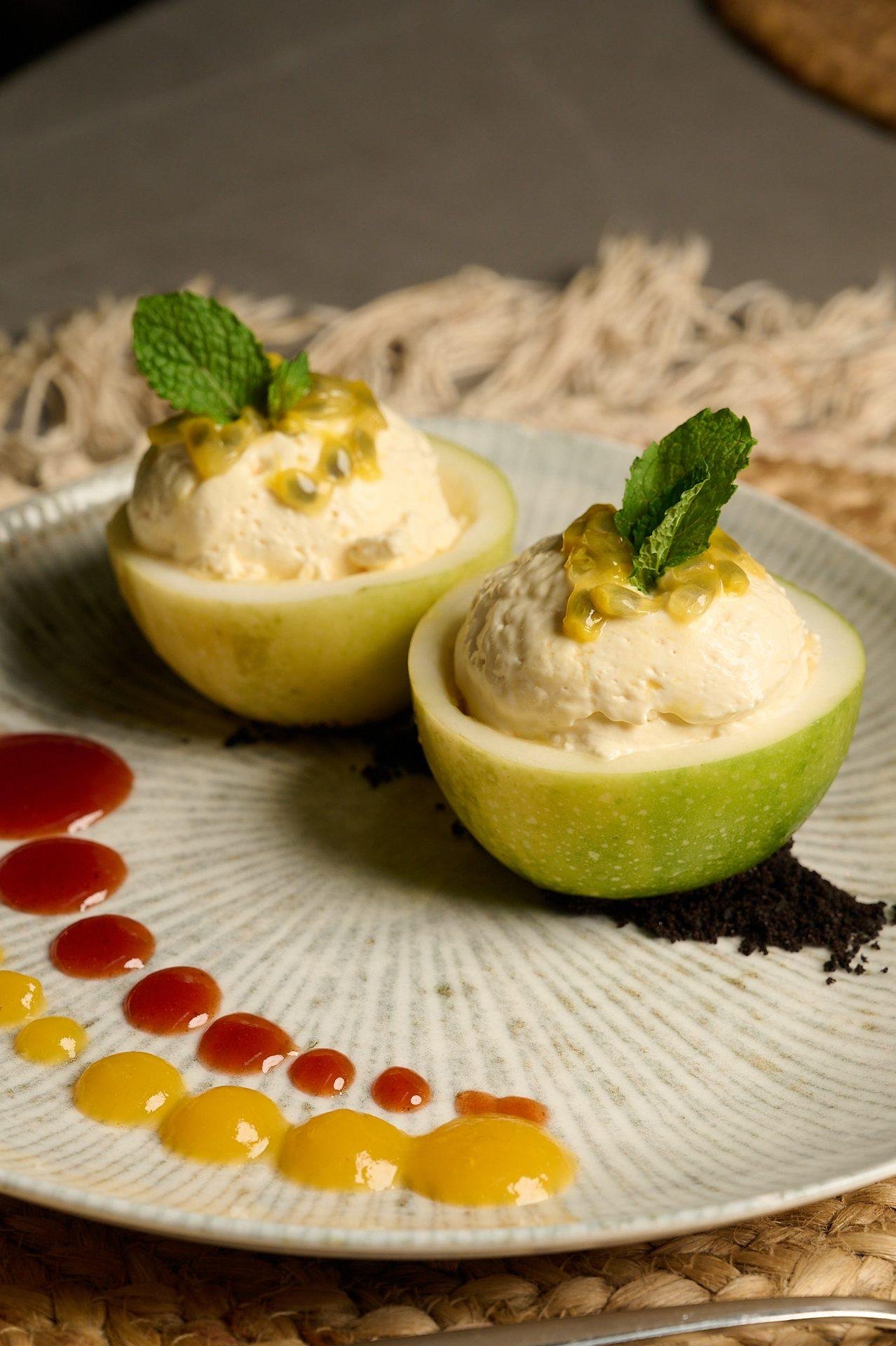 Aguacate relleno con espuma y puntos de salsa en plato de autor