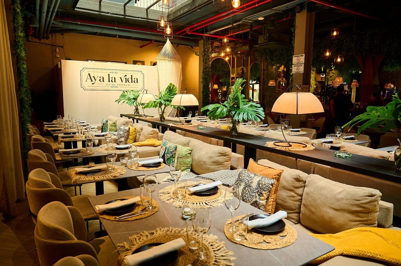 Comedor de Aya la Vida con sofás claros, plantas tropicales y luz cálida