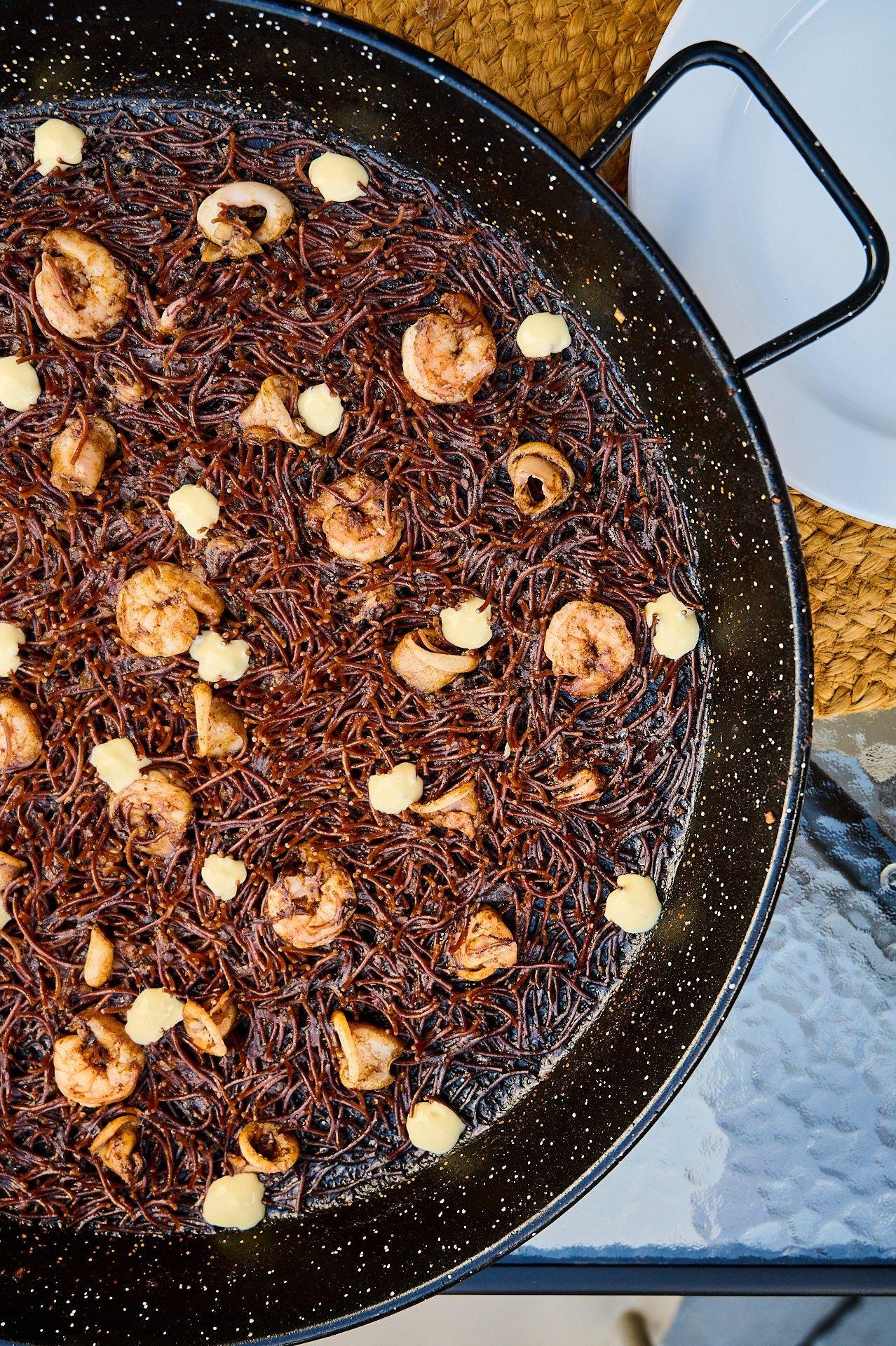Arroz negro con langostinos y alioli en paellera, plato insignia de Santa Rita